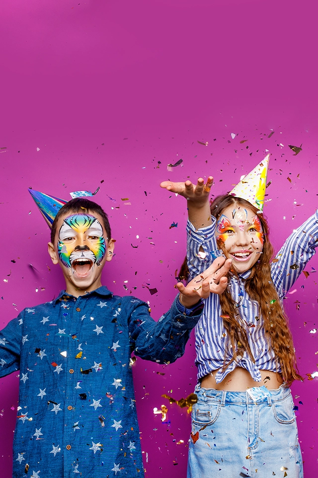 Two children celebrating with confetti and party hats